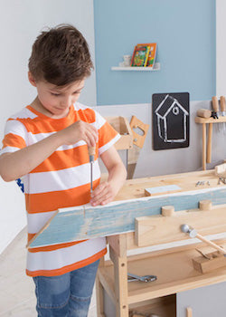Junge spielt mit Holz Werkbank