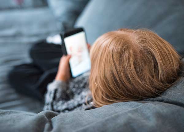 Kind auf Couch mit Smartphone