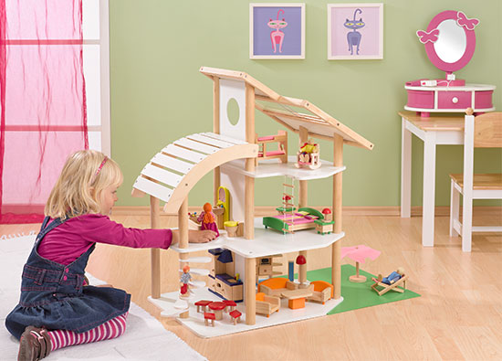 Mädchen spielt mit Holz Puppenhaus