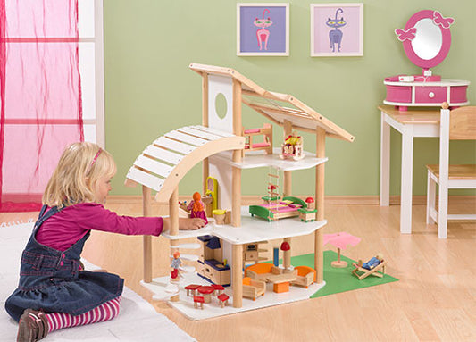 Mädchen spielt mit Holz Puppenhaus