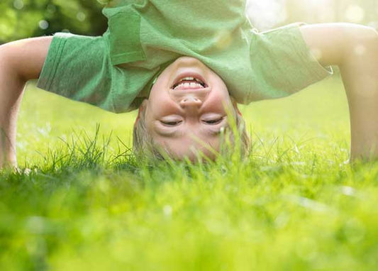 Kind macht Kopfstand im Gras