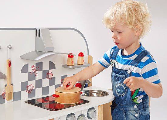 Junge spielt mit Holz Spielküche